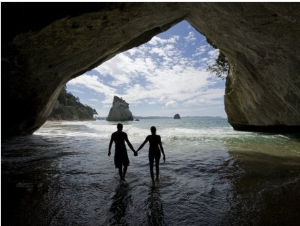 Couple Walking Through Water in a Sea Cave at Cathedral Cove Beach
