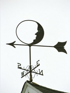 A Man In The Moon Weather Vane on a Roof Top