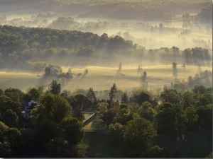 Aerial View of a Farm at Twilight with Sunlight Streaking Through the Mist