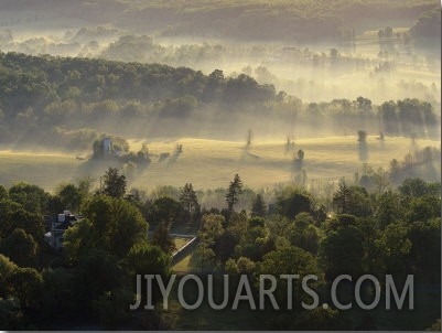 Aerial View of a Farm at Twilight with Sunlight Streaking Through the Mist